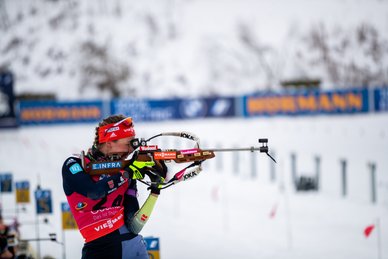 Eine Biathletin zielt mit dem Gewehr