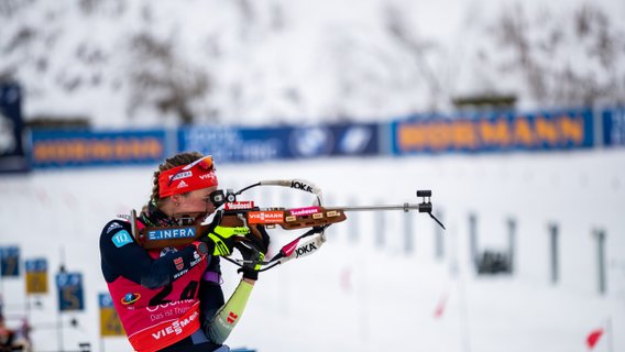 Eine Biathletin zielt mit dem Gewehr